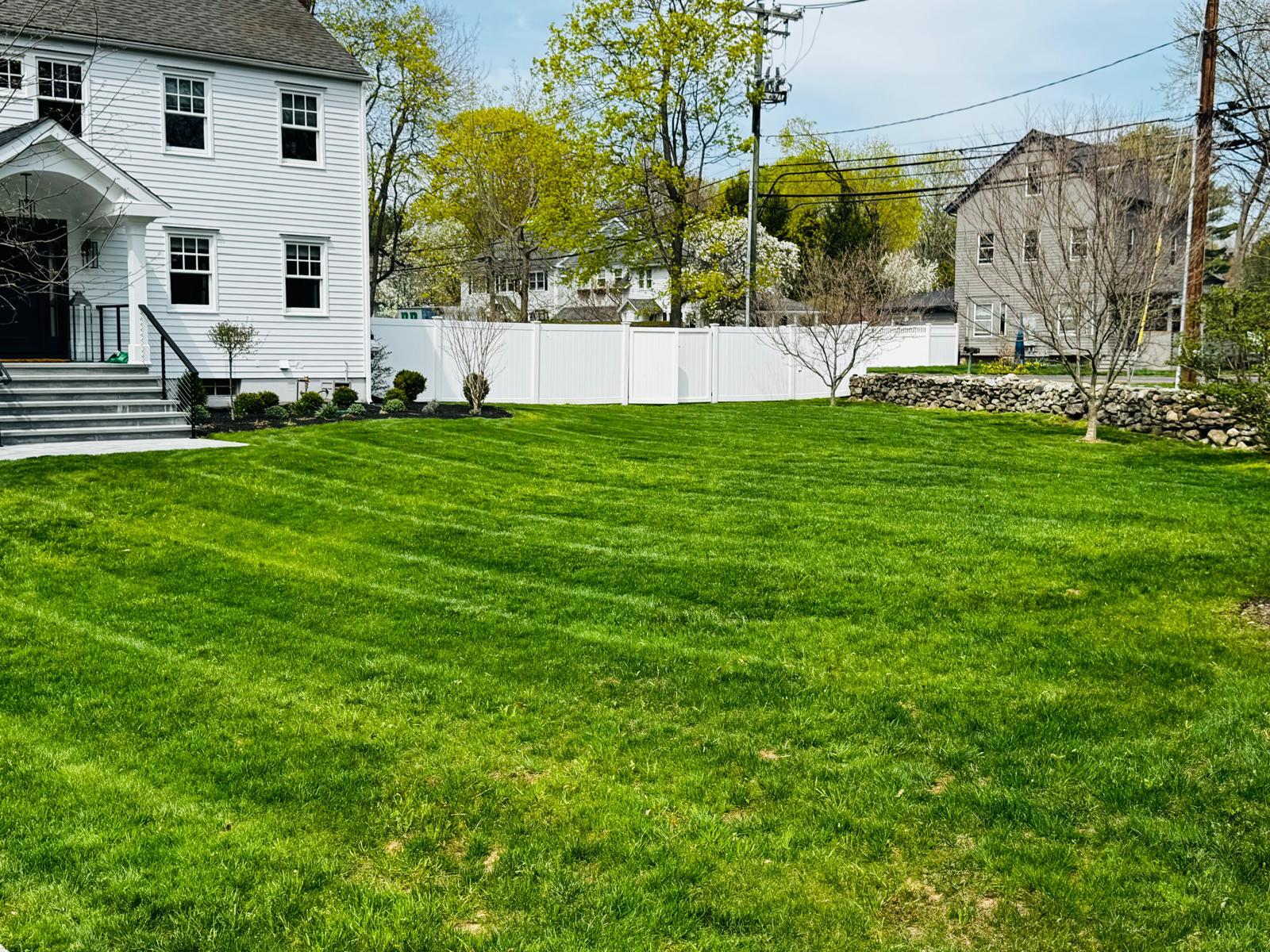 Lush striped backyard lawn seen from a stone patio
